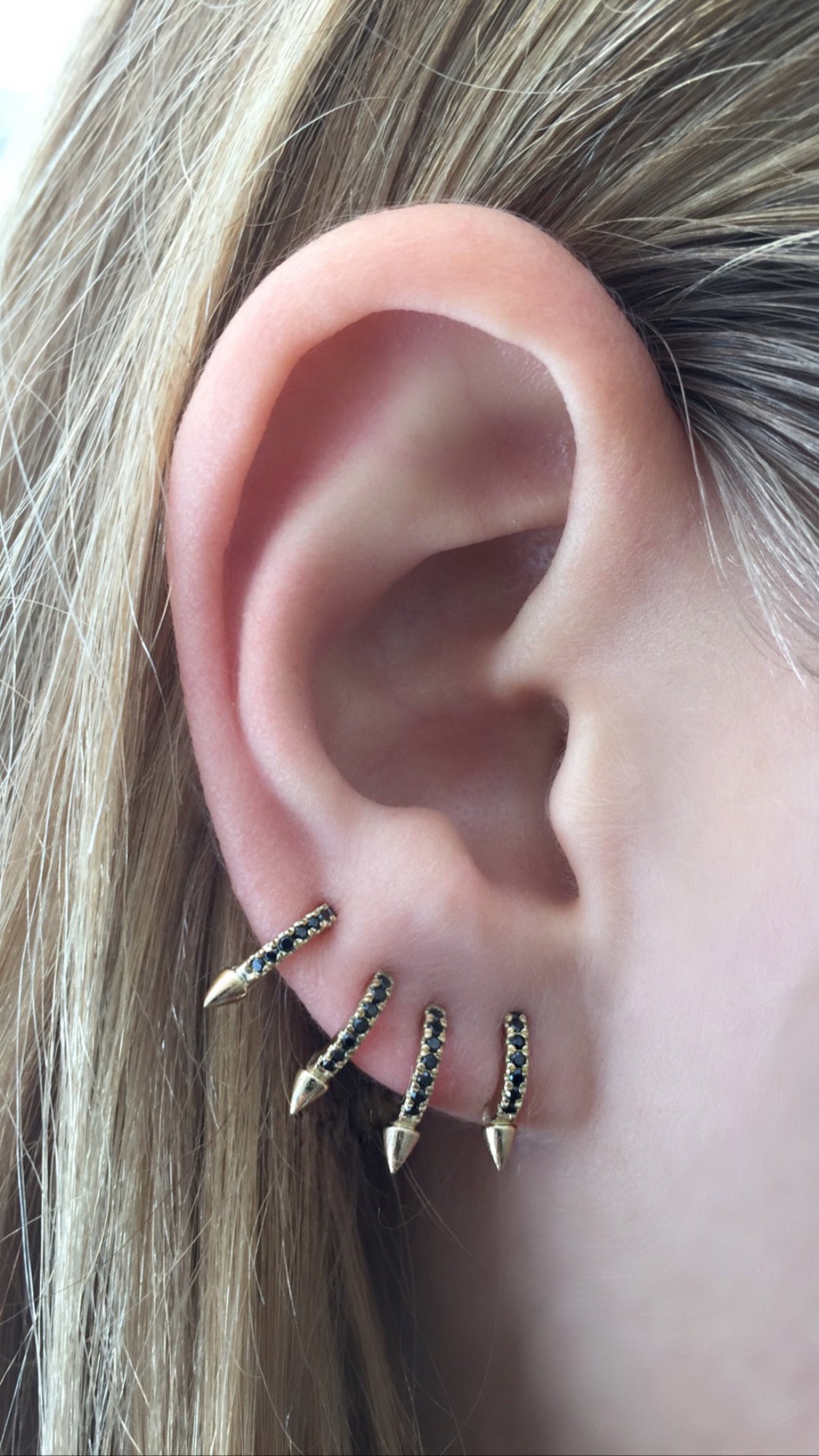 Close-up of an ear with gold spike earrings