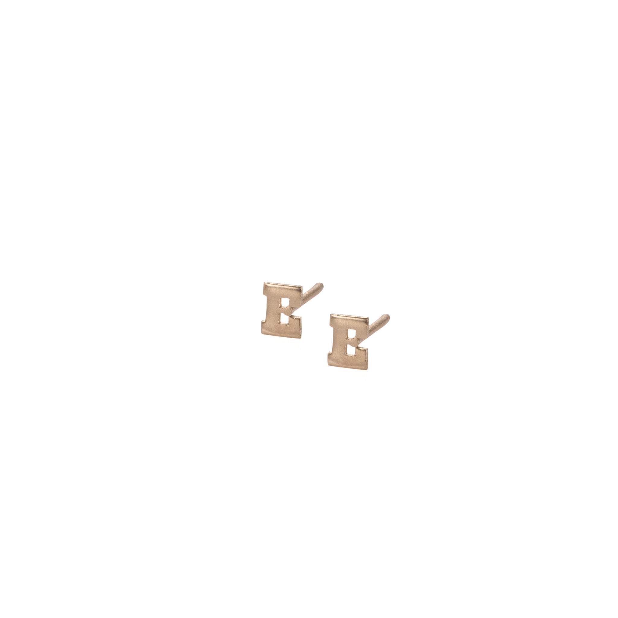A pair of beige 14k gold stud earrings with the letter 'E' on each.